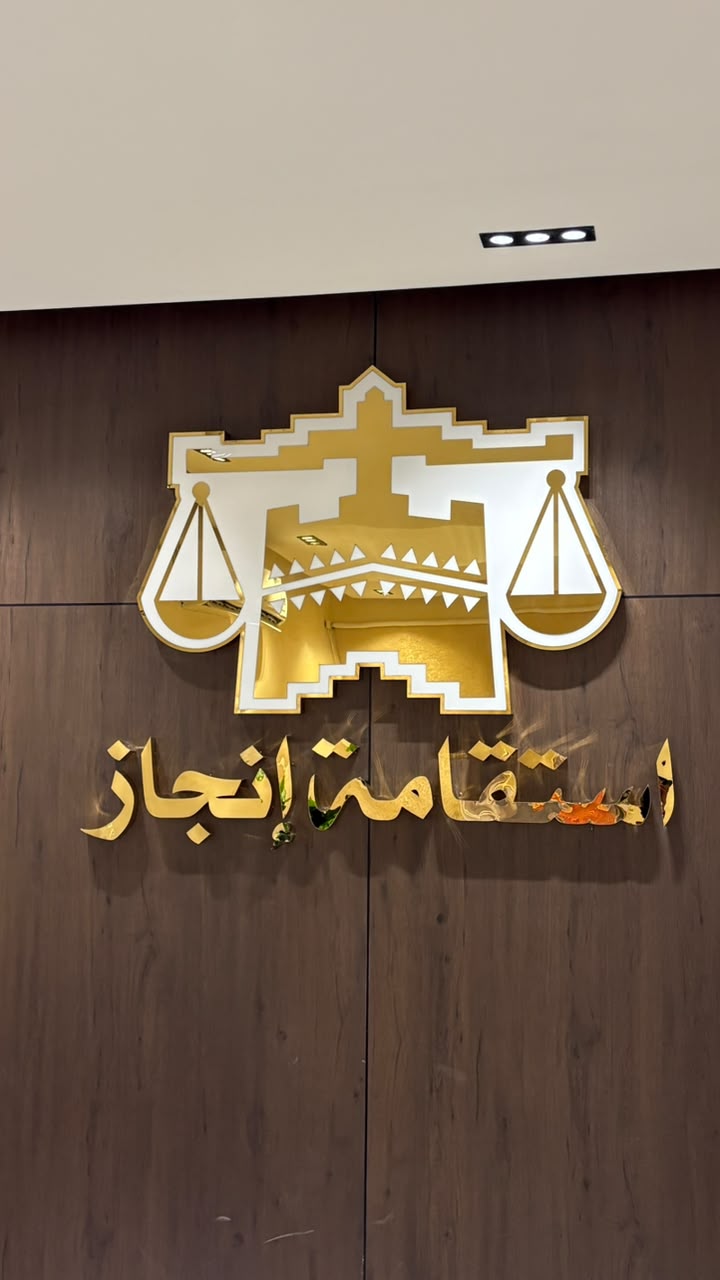 جدار مكتب استقامة إنجاز للمحاماة والاستشارات القانونية — شعار المكتب الذهبي على خلفية خشبية